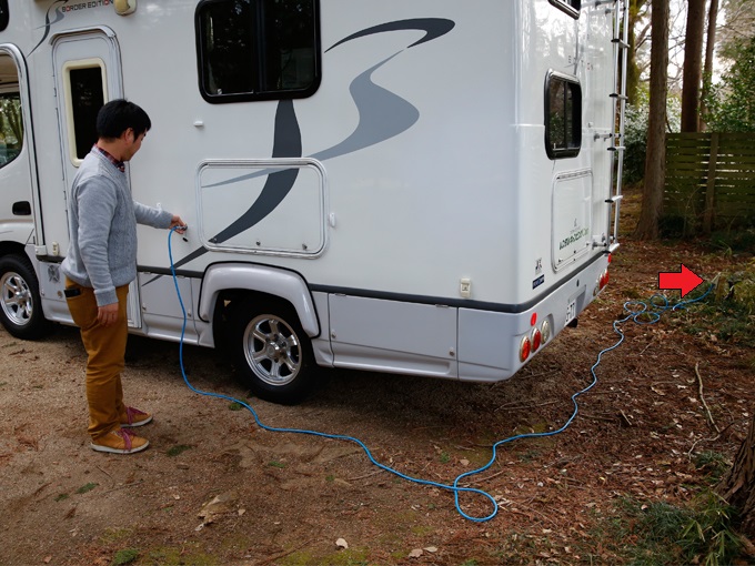 ▲写真右側、矢印の部分が、区画に設置された電源ソケットです。青い電源コードはキャンピングカーに装備されているので用意する必要はありません。お家のコンセントと同じように、抜けないようにしっかりと差し込みます
